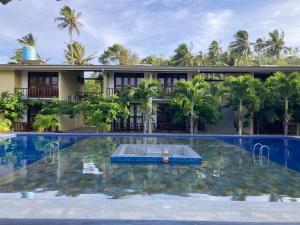 a swimming pool in front of a building with a resort at Handagedara Resort & Spa in Mirissa