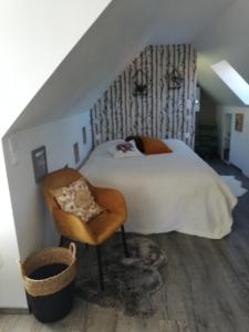 ein Schlafzimmer mit einem Bett und einem Stuhl im Dachgeschoss in der Unterkunft O loft des Croisiens in Saint-Quentin-Lamotte-Croix-au-Bailly