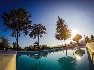 a swimming pool with trees and the sun reflecting in the water at Cabañas LA IRMA in Villa Ciudad Parque