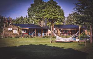 a log cabin with a hammock in front of a house at Cabañas LA IRMA in Villa Ciudad Parque