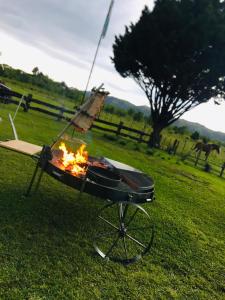 a barbecue grill with a fire in a field at Cabañas LA IRMA in Villa Ciudad Parque
