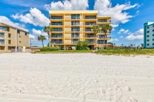 a yellow apartment building on the beach with a sandy beach at Trillium 2A - Premier in St. Pete Beach
