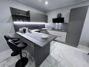 a black and white kitchen with a counter and a stool at Le Porte luxury apartment in Aosta