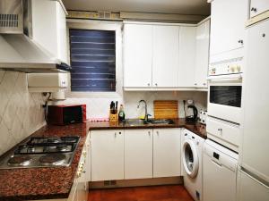 La cuisine est équipée de placards blancs, d'un évier et d'une cuisinière. dans l'établissement CB88, à Barcelone