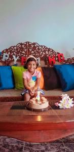 ワドゥワにあるKuma Beach side Villaの誕生日ケーキを持ってソファに座っている少女