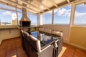 um quarto com uma mesa, cadeiras e janelas em Vista Mar em Porto Santo