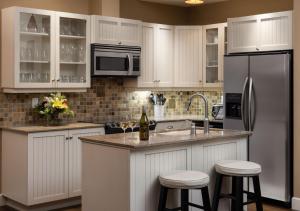 a kitchen with white cabinets and a refrigerator and stools at The Outback Lakeside Vacation Homes in Vernon