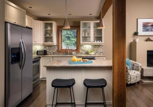 a kitchen with a refrigerator and two bar stools at The Outback Lakeside Vacation Homes in Vernon