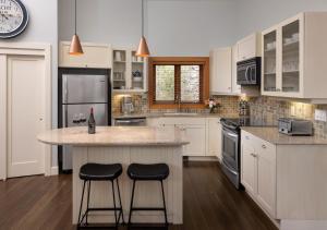 a kitchen with two stools at a kitchen island at The Outback Lakeside Vacation Homes in Vernon