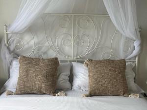 een bed met een wit hoofdeinde en 2 kussens bij La Casa di Nina in La Maddalena