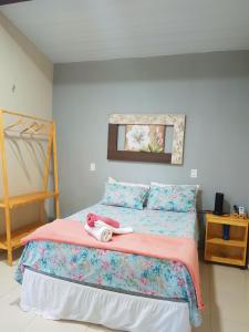 a bedroom with a bed with a pink comforter at Vila Vintém Chalés in Praia de Moitas
