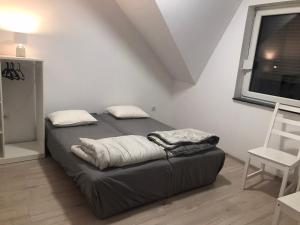 Bett in einem Zimmer mit einem Stuhl und einem Fenster in der Unterkunft Cozy in Powidz