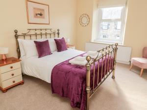 um quarto com uma cama com lençóis roxos e uma janela em 19 Duke Street em Alnwick