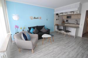 een woonkamer met een bank en stoelen en een keuken bij Haus Norderhoog Wohnung 80 in Westerland