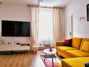 a living room with a yellow couch and a flat screen tv at CozyHome The Castle Apartment - Spacious, quiet, high ceiling in Bratislava