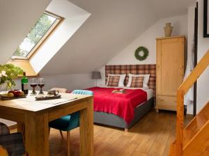 a bedroom with a bed with a red blanket and a table at Apartamenty U Harrego I Przy Stawie Spa in Kudowa-Zdrój