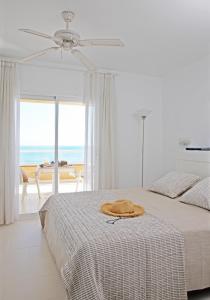 een witte slaapkamer met een bed met een hoed erop bij Apartamentos Golf Mar by La Costa Resort in Pals