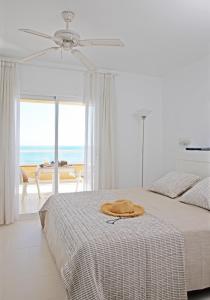 a white bedroom with a bed with a hat on it at Apartamentos Golf Mar I & II by La Costa Resort in Pals