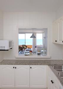 a kitchen with white cabinets and a view of the ocean at Apartamentos Golf Mar by La Costa Resort in Pals