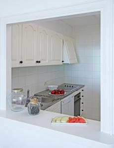 a kitchen with white cabinets and a plate of fruit on a counter at Apartamentos Golf Mar by La Costa Resort in Pals