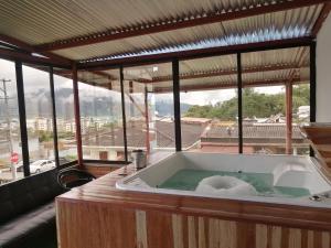 a bath tub in a room with a large window at Hostal spa casa de piedra con jacuzzi in Santa Rosa de Cabal