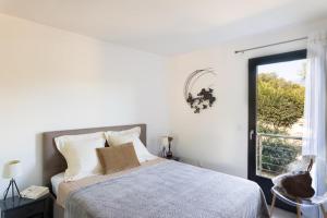 a white bedroom with a bed and a window at Terra di sole in Pianottoli-Caldarello