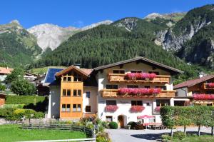 a building with flowers on the balconies in front of mountains at Pension Roman in Pettneu am Arlberg