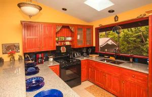 a kitchen with wooden cabinets and a large window at Hawaiian Sunrise Vacation House in Pahoa