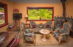 salon z kanapą, krzesłami i oknem w obiekcie Hawaiian Sunrise Vacation House w mieście Pahoa