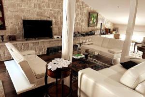 Elle comprend un salon doté d'un mobilier blanc et d'un mur en pierre. dans l'établissement Casa de los Recuerdos, à Cuéllar