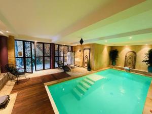 een groot zwembad in een kamer met houten vloeren en ramen bij Le Clos Des Anges in Bagnols