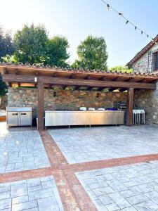 a barbecue under a wooden pergola on a patio at Mas Segart in Santa María de Palautordera