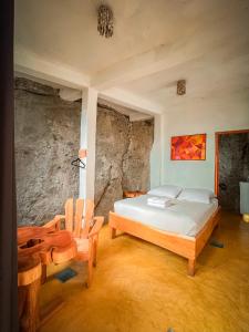 a bedroom with a bed and two wooden chairs at Lush Atitlán in San Marcos La Laguna