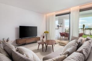 sala de estar con sofá y TV de pantalla plana en Exclusive New Apartment within Santa Clara and Marbella Golf & Country Club, en Marbella