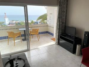 a living room with a television and a balcony with a view at MEERBLICK BEACH-APARTMENT Monte Rojo in San Agustin