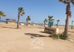 einen Strand mit Palmen und ein Schild darauf in der Unterkunft Taj Home ,cozy mangroovy 2BR apartment..pool&Beach access in Hurghada