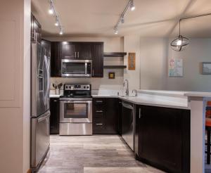 eine Küche mit Küchengeräten aus Edelstahl und schwarzen Schränken in der Unterkunft Zephyr Mountain Lodge Premium-Rated 1102 in Winter Park