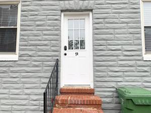 uma porta branca numa casa de tijolos com um caixote do lixo verde em Modern cozy 1BD/1BA Apt in Federal Hill em Baltimore