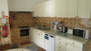 uma pequena cozinha com armários brancos e um lavatório em Casa do Jorge em Leiria