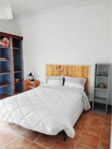 a bedroom with a large white bed with a wooden headboard at Casa Terra Cota - Almada in Almada
