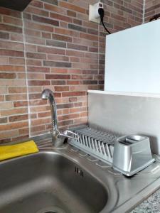 a kitchen sink with a soap dispenser next to a brick wall at Casa Terra Cota - Almada in Almada