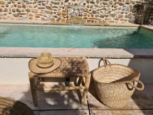 un cappello di paglia seduto su una sedia accanto alla piscina di La parenthèse Thuir piscine privée et chauffée a Thuir