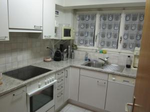 a white kitchen with a sink and a microwave at 2.5-Zimmer-Wohnung Balkon freie See- und Bergsicht, Garage PPe in Engelberg