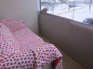 a bed with a red and white comforter and a window at 2.5-Zimmer-Wohnung Balkon freie See- und Bergsicht, Garage PPe in Engelberg