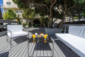eine Terrasse mit 2 Stühlen und einem Tisch mit Getränken darauf in der Unterkunft Hotel Arte del Rey in Pinamar