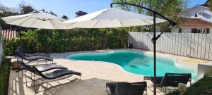 ein Swimmingpool mit zwei Sonnenschirmen und Stühlen und ein Swimmingpool in der Unterkunft Hotel Arte del Rey in Pinamar