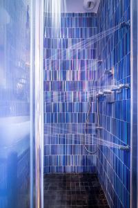 a blue tiled bathroom with a shower and a tub at Apostrophe Hôtel in Paris