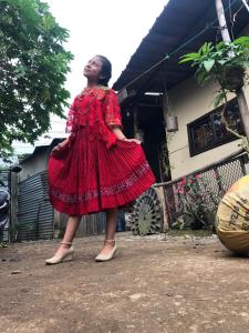 a woman in a red dress standing in front of a house at Cora Izone in Cob&aacute;n
