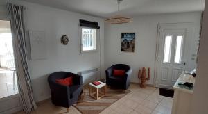 a living room with two chairs and a table at Maison au coeur de Meschers - proche des plages in Meschers-sur-Gironde +25 photos