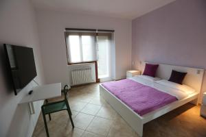 een slaapkamer met een bed met paarse lakens en een tv bij Casa Michela in LʼAquila